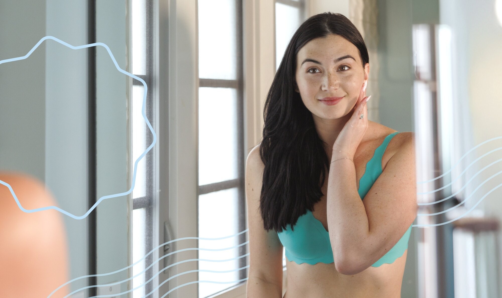 Woman holding looking in a mirror and holding her hand to her face, contemplating the laser hair removal aftercare steps